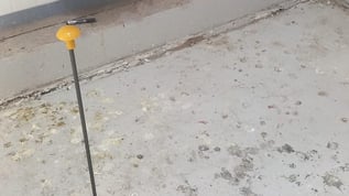 Close up view of re-leveled floor closing gap with wall and one injection tube