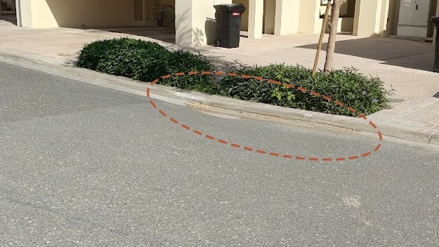 What causes road depressions near landscaped areas?