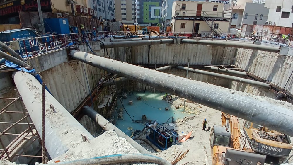 view of construction site excavation with water at the base and shoring around the site