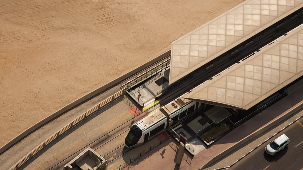 Aerial view of Dubai metro station with train tracks adjacent to the sand