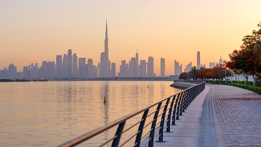View along seawall with pedestrian walkway and Dubai skyline in background