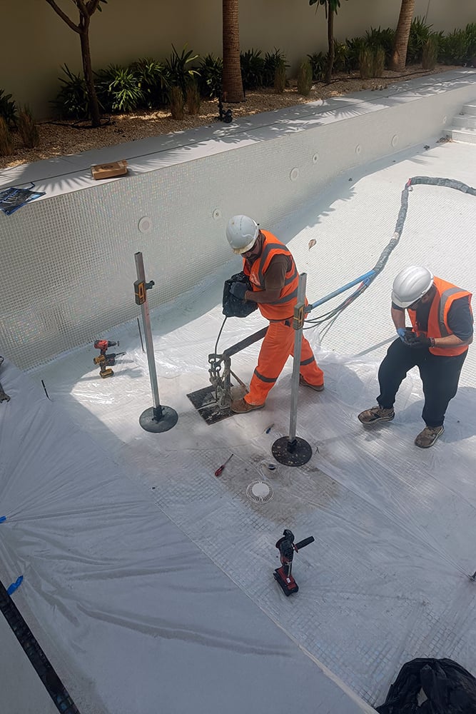 Empty swimming pool being treated for ground settlement using geopolymer injections