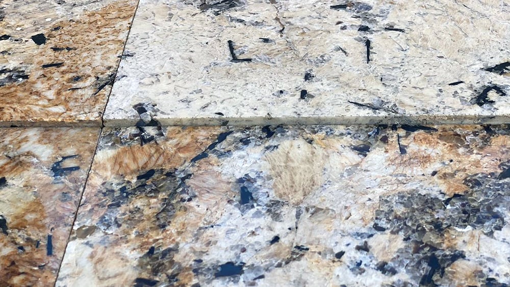 closeup view of tile "popping" at joint due to ground settlement