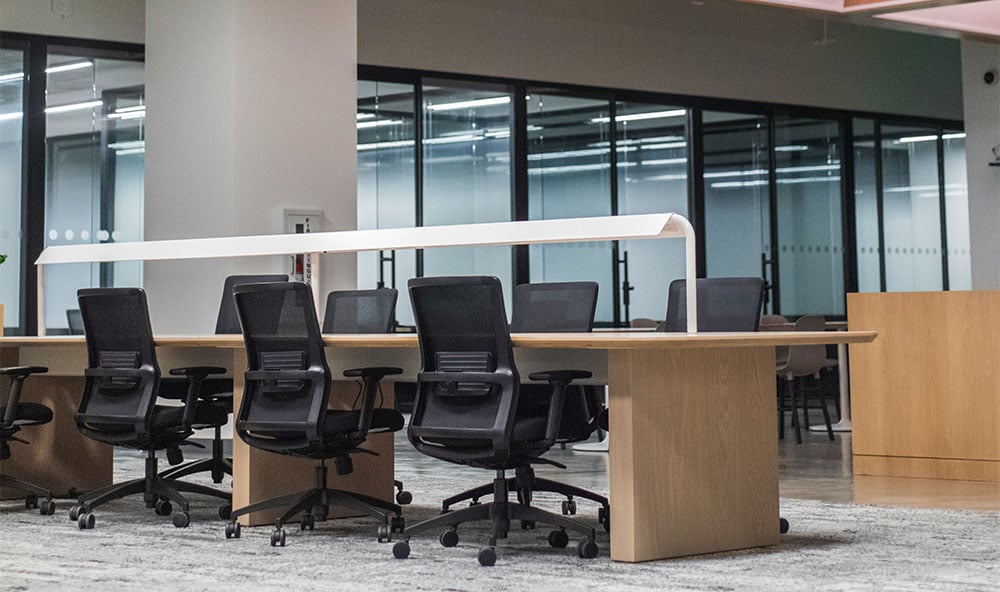 Kontorslandskap med stolar, bord och lampor.