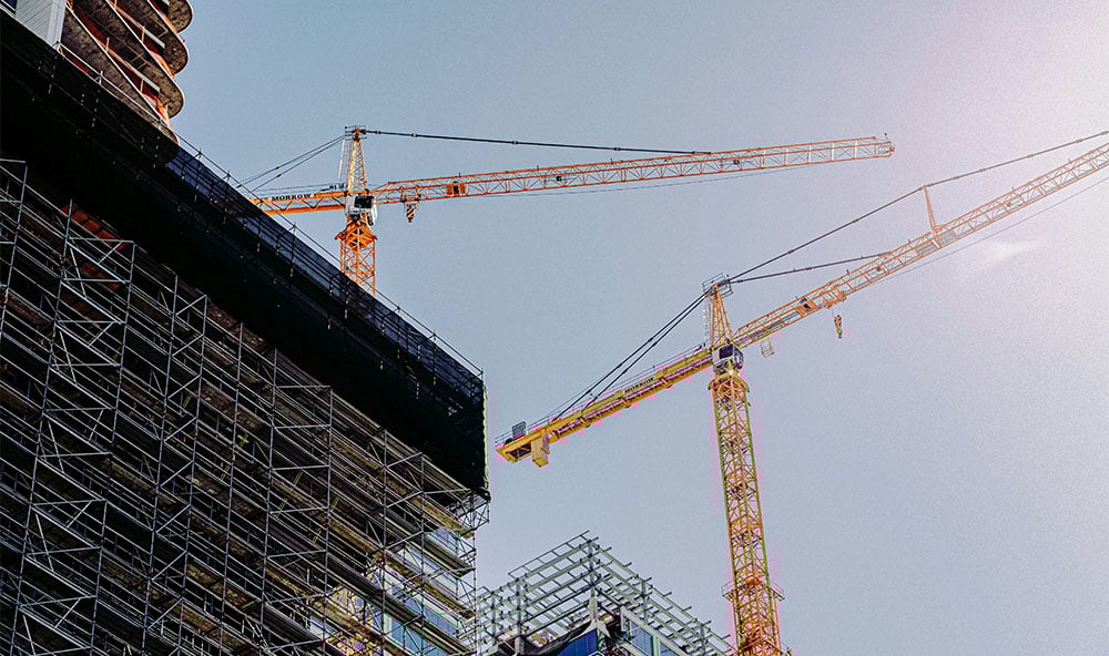 Bild på utsidan av en byggnadskonstruktion med lyftkranar högt upp.