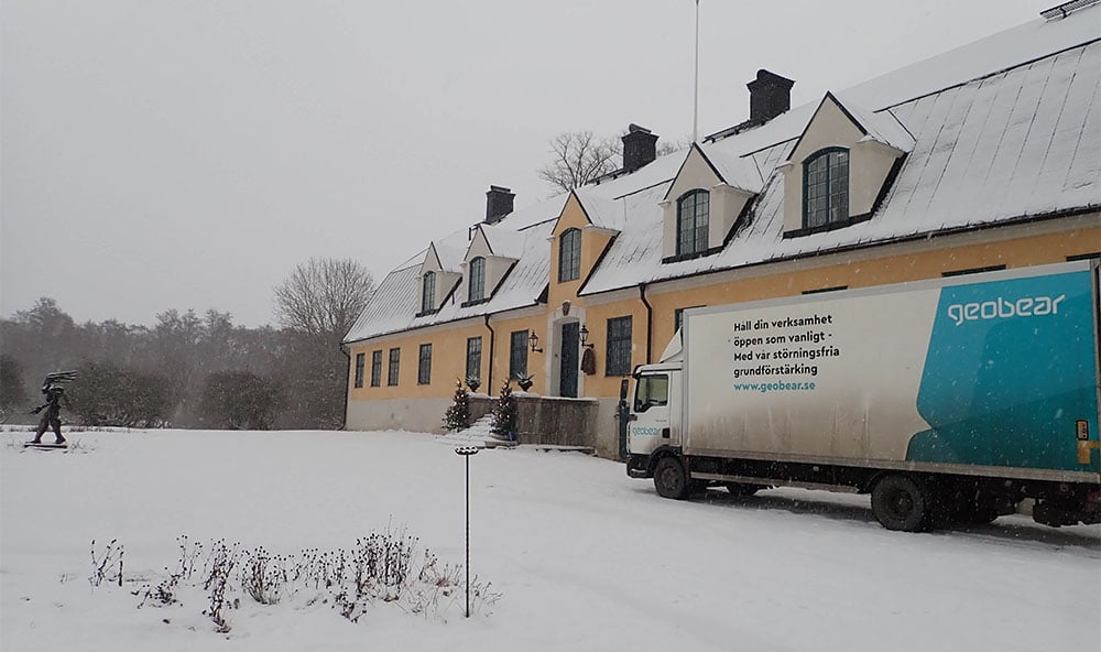 Geobears lastbil parkerad utanför en kulturhistorisk byggnad i Sverige i vackert vinterväder med snö på marken.