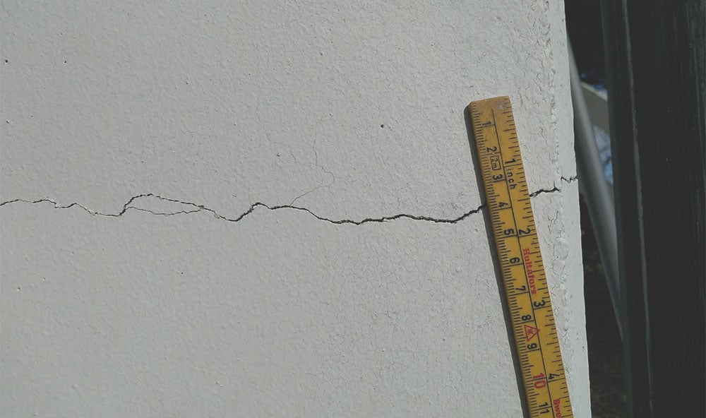 Mått på spricka i vit husvägg.