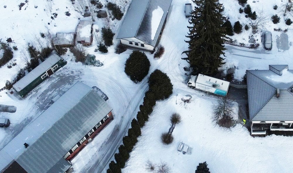 Drönarbild över bostadsomåde i fint vinterväder med Geobears lastbil parkerad för att utföra markförstärkning med geopolymer.