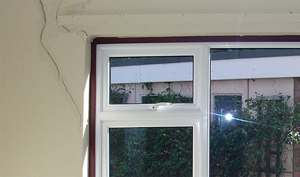 Kärvande fönster och sättningssprickor i väggen bredvid.