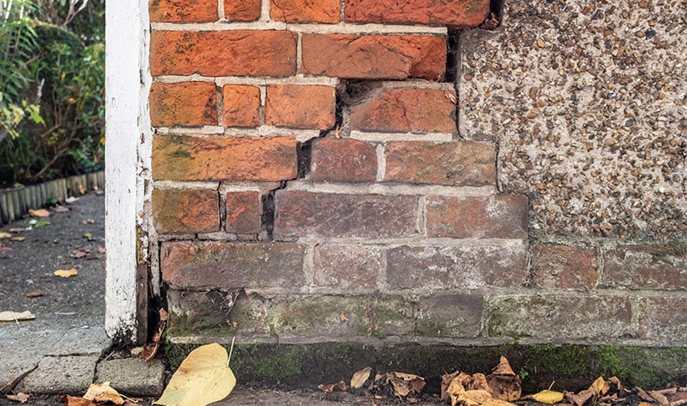 Ytterhörn av bostadshustegel med synliga sättningssprickor i tegelverket