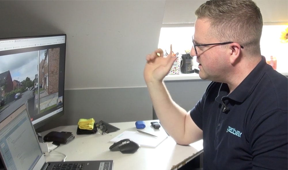 En Geobear-expert som sitter vid ett skrivbord genomför ett videobesök med en klient. Deras datorskärmar är synliga medan experten pratar.