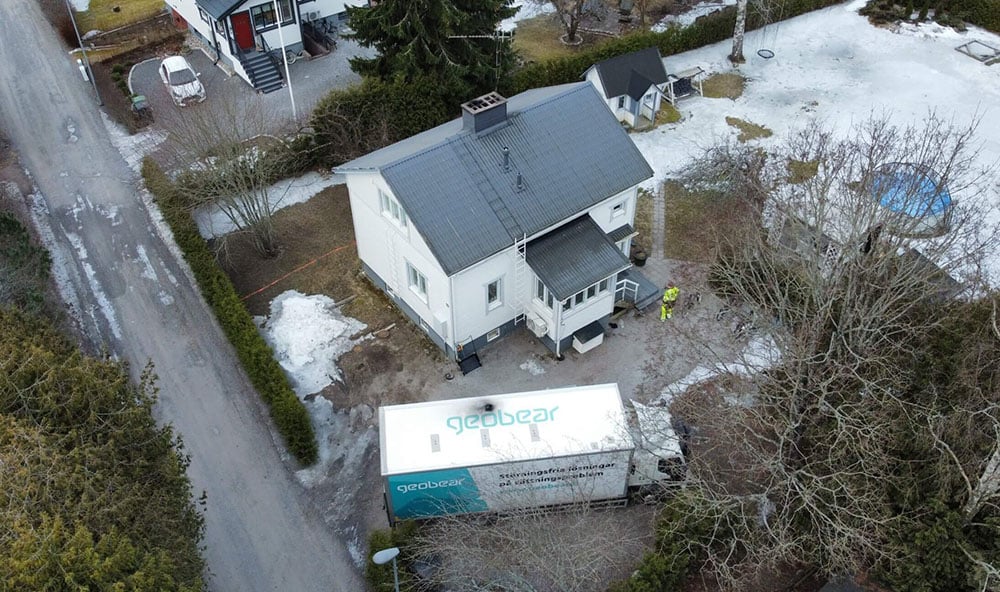 Drönarbild över vit villa med Geobears lastbil på plats för injektering med geopolymer för att åtgärda sättningar.