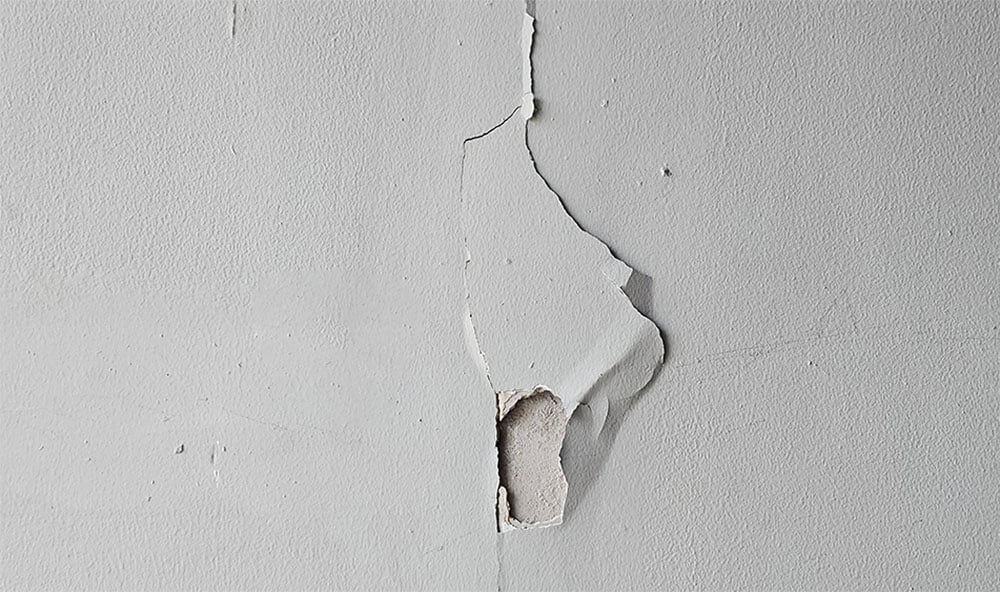 Trasig vit tapet på grund av sättningar.