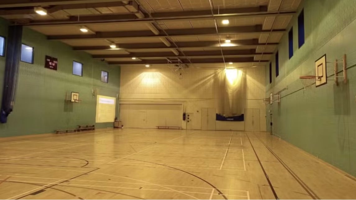 View of inside gymnasium with wood floors and green walls