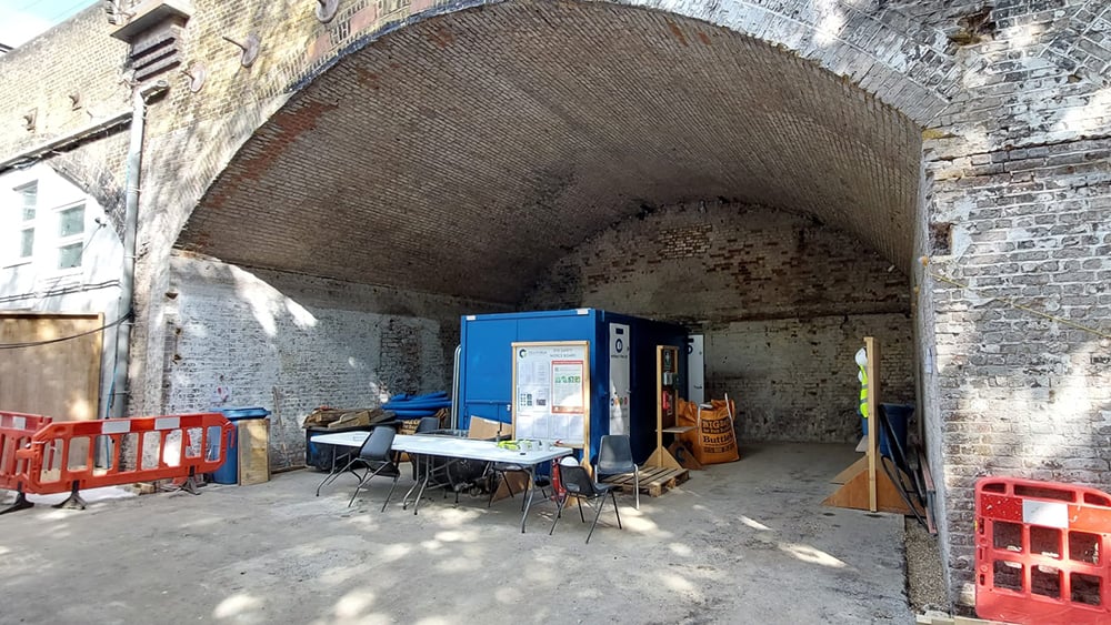 Exterior view of historic rail arch with safety barriers on the left and right sides.