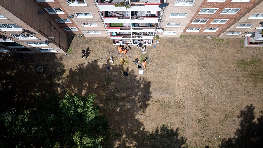Aerial view looking down at a block of flats terraces where Geobear techs are working at ground level