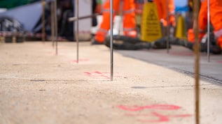Close up view of numbered injection points on a concrete slab with Geobear techs out of focus in the background.