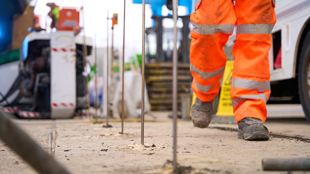 View of injection tubes inserted into a concrete slab with a Geobear tech walking in the background