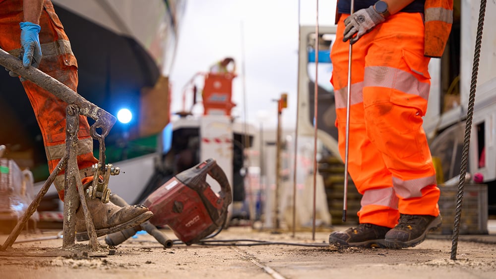 View of Geobear techs working on installing injection tubes in a concrete slab with tools in background.