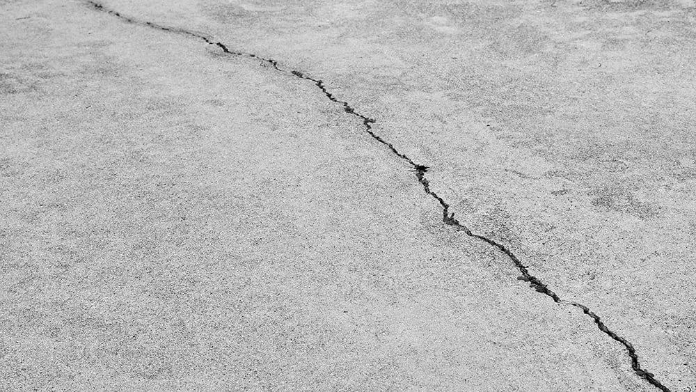 Close up view of large diagonal crack in a cement slab floor