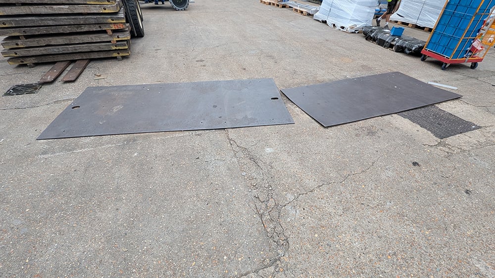 Cracked and uneven concrete slabs with large steel plates covering to prevent trip and vibration hazards.