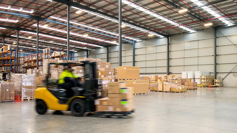 Forklift carrying a load in a warehouse setting.