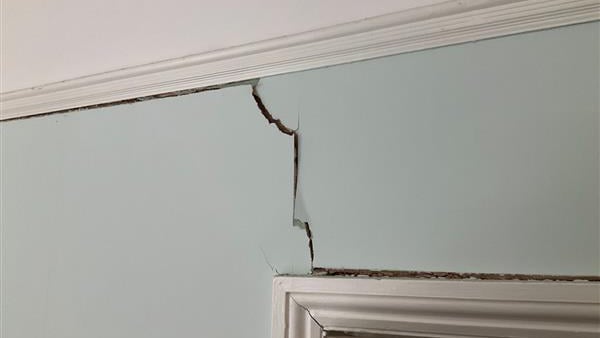 Internal wall subsidence crack extending from the top of a door frame upwards to the ceiling and continuing towards the left