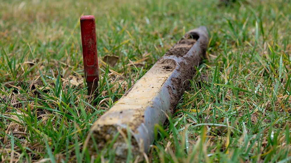 View of soil borehole sample laying in the grass.
