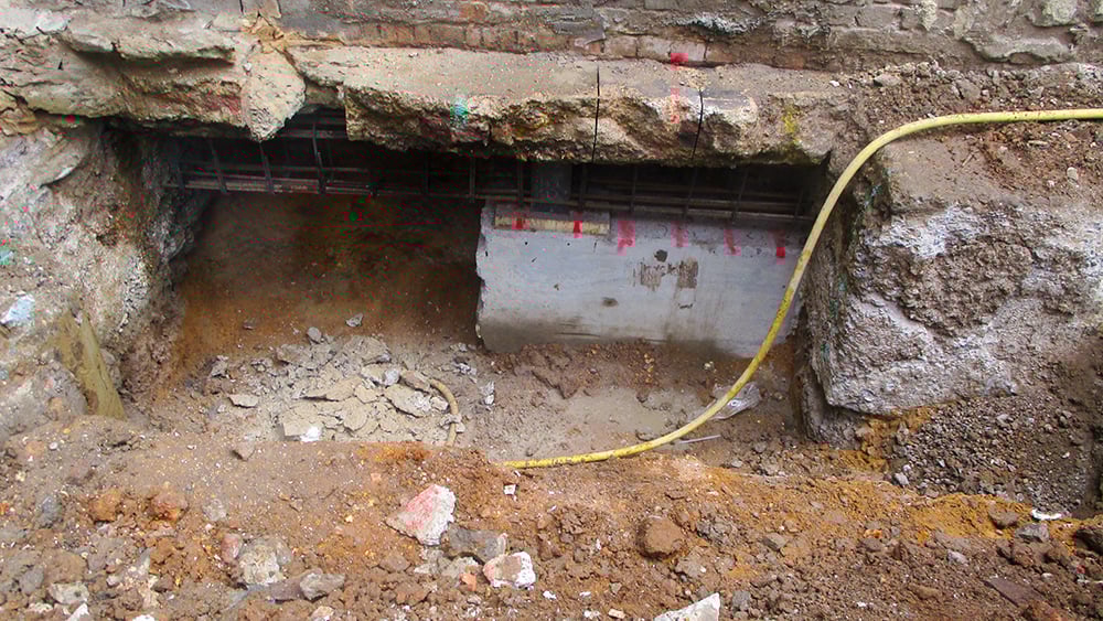 Looking into an exposed home foundation where concrete underpinning is being installed.
