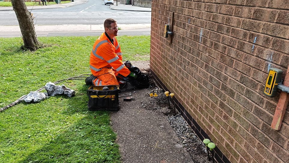 Geobear tech injecting geopolymer along outside brick wall of residential property
