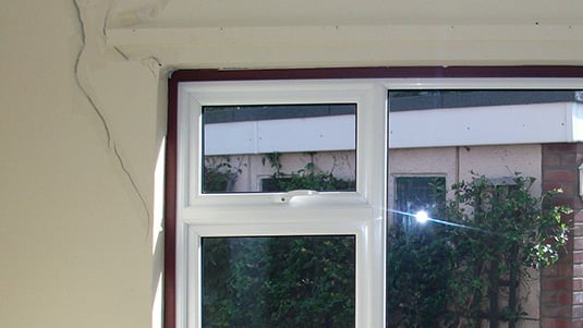Large window frame with adjacent subsidence cracks visible from the frame's left side.