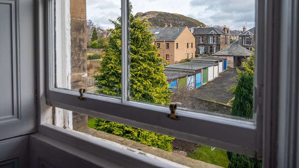 View looking out from inside home through partially opened window.