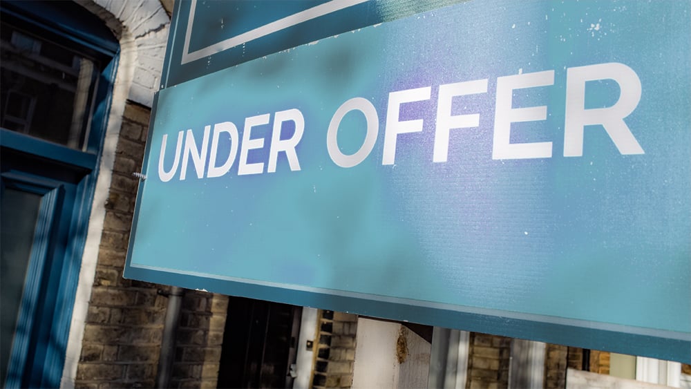 Lower view of a residential for sale sign which reads "under offer"