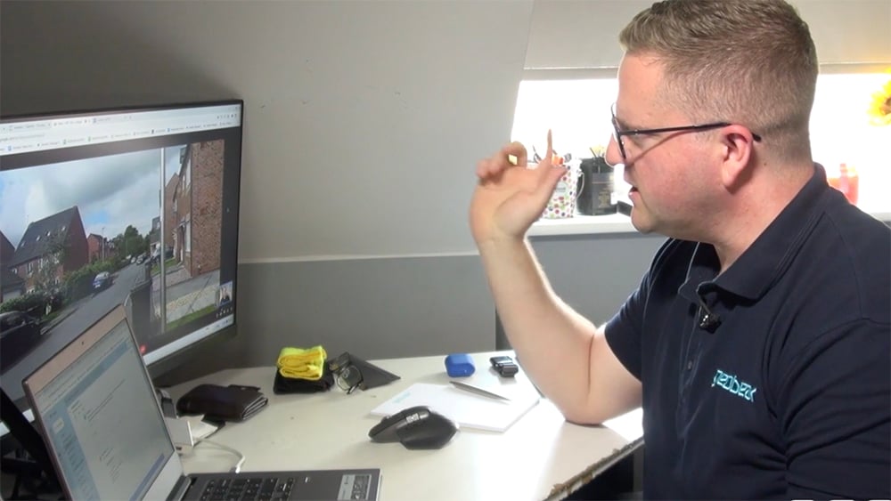 A Geobear expert sitting at a desk conducts a video visit with a client. Their computer screens are visible as the expert talks.
